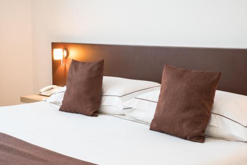 a white bed with two pillows on top of it at Airporthotel Verona Congress & Relax in Dossobuono