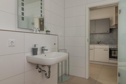 a white bathroom with a sink and a kitchen at Ferienwohnung Bamberg in Bischberg