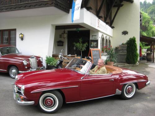 an older man sitting in a red car at Panoramahotel Karwendelhof in Wallgau