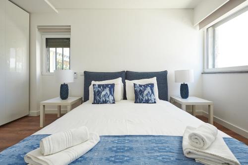 カスカイスにあるOn the Beachの白いベッドルーム(青い枕の大型ベッド付)