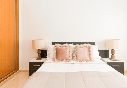 a bedroom with a white bed with two lamps at Residential jardín del pintor - la casa amarilla in Jacarilla
