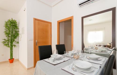 a dining room with a long table with chairs and a mirror at Residential jardín del pintor - la casa amarilla in Jacarilla