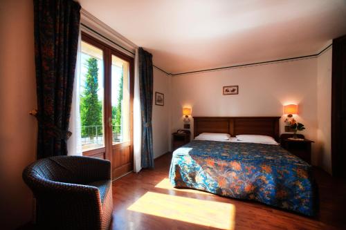 a bedroom with a bed and a window and a chair at Albergo La Lanterna in Sarteano