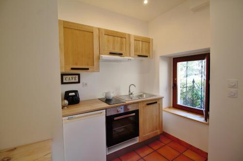 cocina con armarios de madera, fregadero y ventana en La Maison du Canal - Canal Studio en Homps