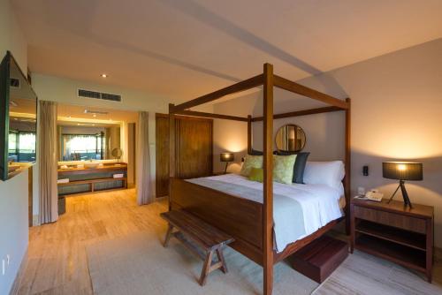 a bedroom with a canopy bed and a bathroom at Kimpton Aluna Resort Tulum by IHG in Tulum