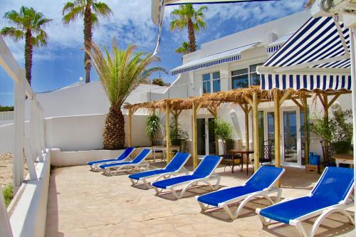 a row of blue chairs and a house with palm trees at Villa sunbeach in Roquebrune-sur-Argens