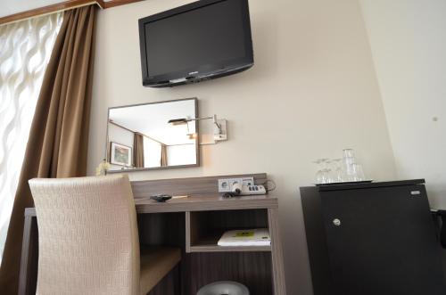 a desk with a mirror and a television on a wall at Hotel Faber in Hoogezand