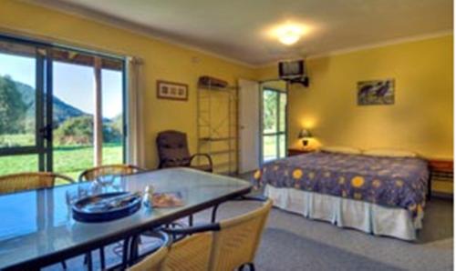 a bedroom with a bed and a table with chairs at Smiths Farm Holiday Park in Linkwater