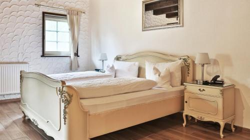a bedroom with a white bed with a nightstand and a window at Hotel Restaurant Mönchhof in Gaggenau