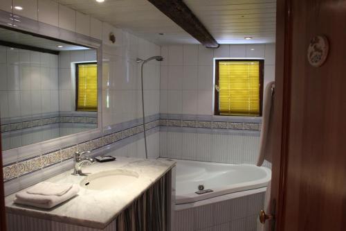 ein Badezimmer mit einem Waschbecken, einer Badewanne und einem Spiegel in der Unterkunft B&B La Tête dans les Etoiles in Weyersheim