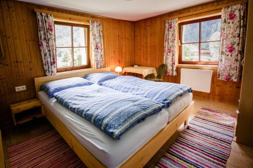 a bed in a room with wooden walls and windows at Pirschenhof in Gschnitz