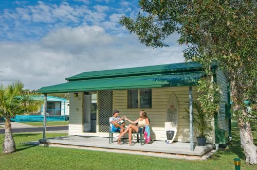 two people sitting on a porch of a tiny house at Glen Villa Resort in Byron Bay