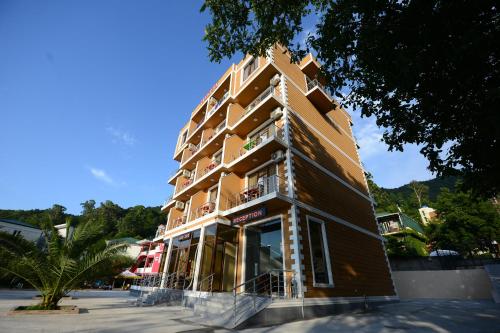 a tall brown building with windows on a street at Medea Kvariati in Kvariati