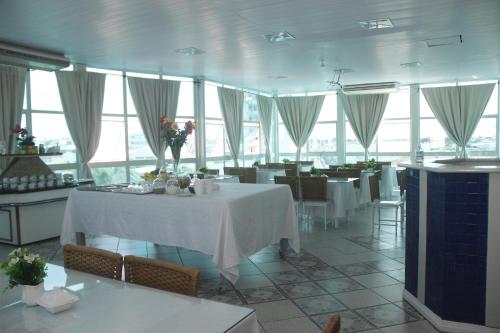 a dining room with a table and chairs and windows at Palace Hotel in Araguari