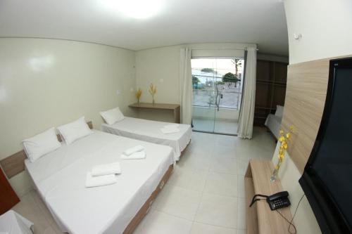 a small room with two beds and a window at Pousada Santo André - O Apóstolo in Juazeiro do Norte
