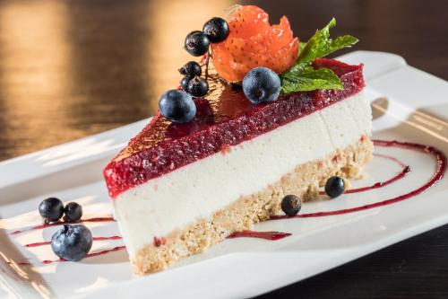 a piece of cake with berries on a white plate at Hotel Roberto Slanic Prahova in Slănic