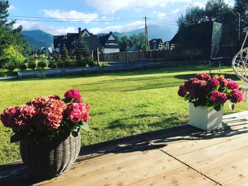 two baskets of flowers on a table with a field at Stylowa Chata in Zakopane