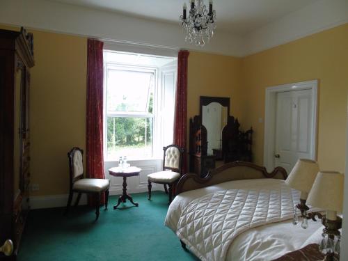 a bedroom with a bed and chairs and a window at Hartley House B&B in Carrick on Shannon