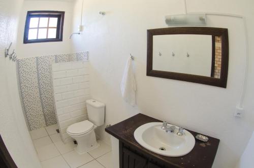 a bathroom with a sink and a toilet and a mirror at Pousada da Encosta in Garopaba
