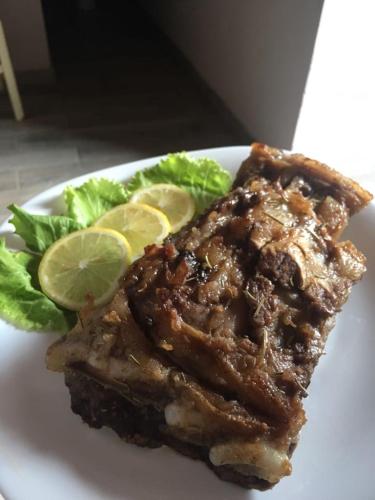 a plate of food with a piece of meat and lettuce at Guest House Flodisa in Theth