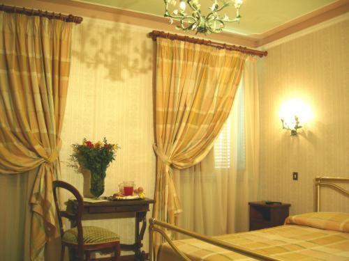 a bedroom with a bed and a table and a window at Hotel Villa San Donino in Città di Castello