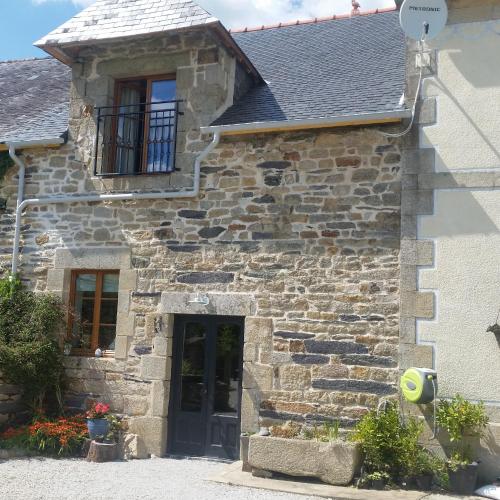 a stone house with a black door and a window at L'Effraie des Clochers in Cast