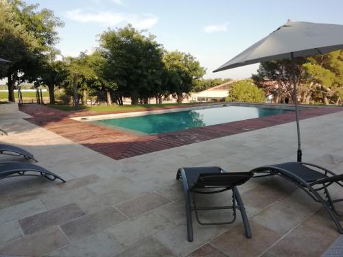a pool with two chairs and an umbrella at Domaine de la Vidalle in Vendres