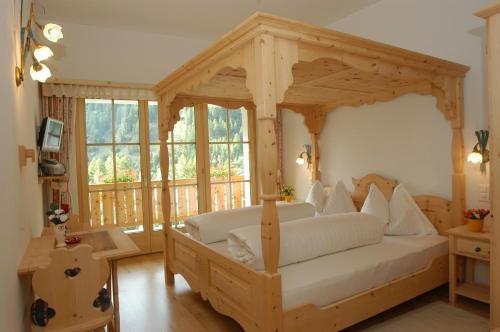 a bedroom with a wooden canopy bed with white pillows at Hotel Crusch Alba Sta Maria in Sta Maria Val Müstair