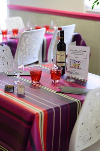 a table with a bottle of wine and glasses on it at Hôtel Juantorena in Saint-Étienne-de-Baïgorry