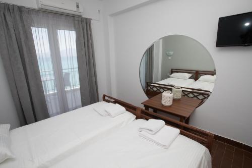 a bedroom with two beds and a mirror at Marzi Boutique Hotel in Nerátza
