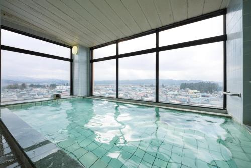 a swimming pool in a building with windows at Annex Royal Hotel in Odate