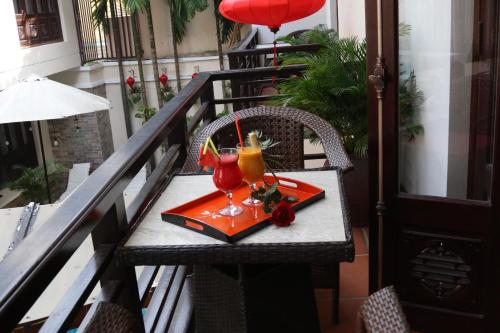 a table on a balcony with two drinks on it at Long Life Riverside Hotel in Hoi An