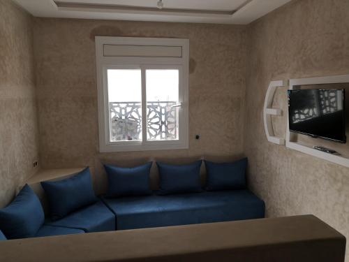 a living room with a blue couch and a window at My Home Mirelft in Mirleft
