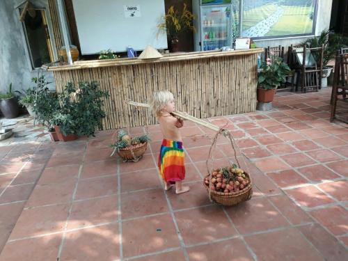 a little child in a colorful dress holding a broom at Tuan Nam Homestay in Ninh Binh