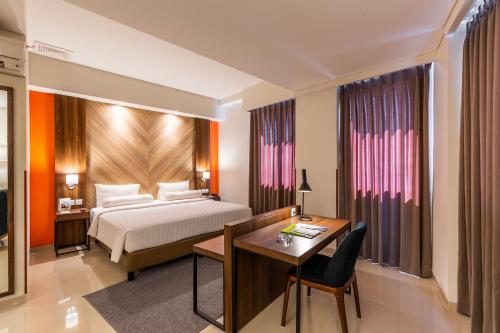 a hotel room with a bed and a desk and a desk at Great Diponegoro Hotel Surabaya in Surabaya