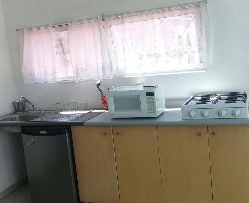 a kitchen with a microwave and a sink and a window at Posada San Cristobal in Cuernavaca