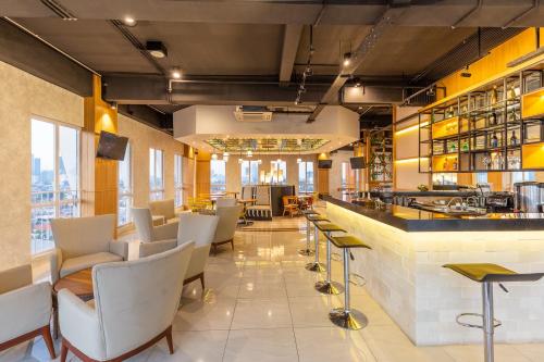 um restaurante com um bar com cadeiras e mesas brancas em Great Diponegoro Hotel Surabaya em Surabaya