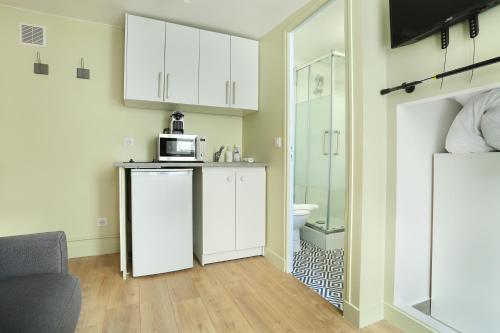 une cuisine avec des placards blancs et un four micro-ondes sur un comptoir dans l'établissement Rent a Room - Cosy studio, à Paris