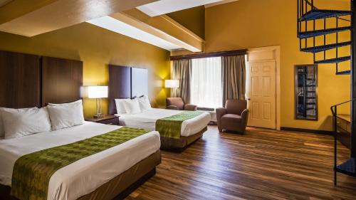 a hotel room with two beds and a chair at Best Western Plaza Inn in Pigeon Forge