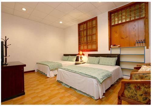 1 dormitorio con 2 camas y escritorio con lámpara en 初鹿敦親牧鄰民宿, en Chulu