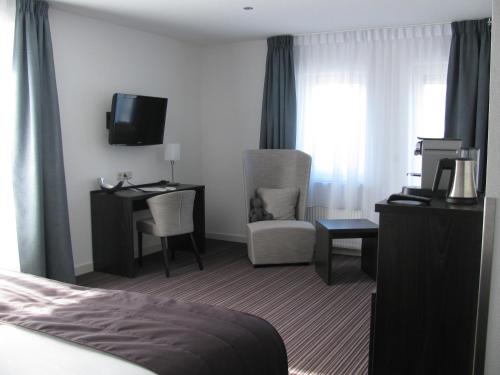 a hotel room with a bed and a desk and a tv at Boutique Hotel de Zwaluw in De Koog