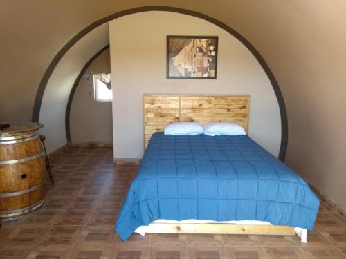 Un dormitorio con una cama azul y un barril en Cabañas Valle de Guadalupe, en La Amplación