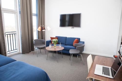 a living room with a blue couch and a table at Best Western Hotel River C in Karlstad
