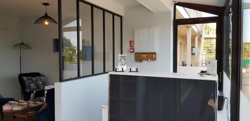 a kitchen with a white counter and a window at Hôtel L'ideal le Mountbatten in Arromanches-les-Bains