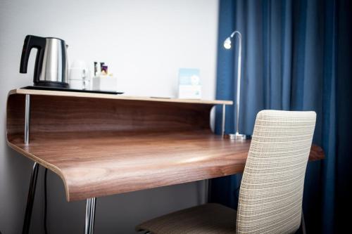 a wooden desk with a chair next to a blue curtain at Best Western Hotel River C in Karlstad