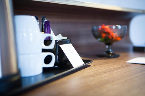 a table with a cup of coffee and a bowl of flowers at Best Western Hotel River C in Karlstad