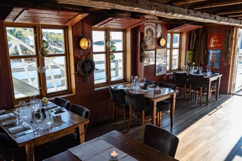 ein Restaurant mit Holzwänden, Tischen und Fenstern in der Unterkunft Nyvågar Rorbuhotell - by Classic Norway Hotels in Kabelvåg