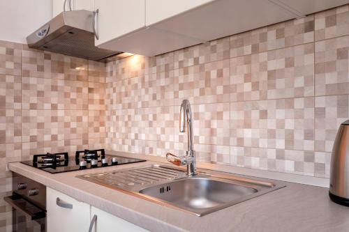 um lavatório de aço inoxidável numa cozinha com azulejos cor-de-rosa em Apartments Marković em Stari Grad