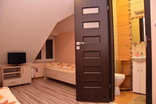 - une salle de bains avec un lit et une porte dans la chambre dans l'établissement Dom Weselny Jagiełło, à Dobrzelin
