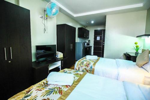 a hotel room with two beds and a flat screen tv at The Studio 87 Residences in Manila